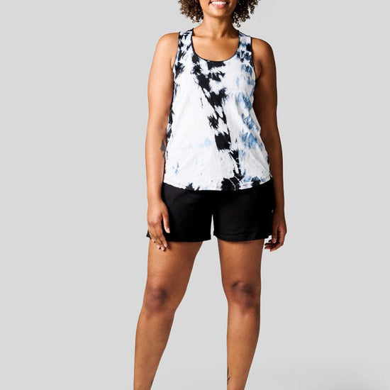 Women wears a white Tie Dye tank top, black shorts and Nike Air Max shoes.
