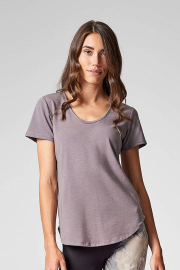 A brunette wears a light grey t-shirt made for barre, yoga and every day conscious consumers.