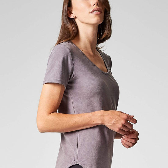 A brunette shows the side view of a short sleeve t-shirt in light soft grey.
