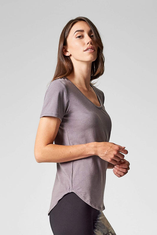 A brunette shows the side view of a short sleeve t-shirt in light soft grey.