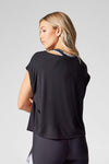 A blond woman is shown from the back wearing a black box shaped t-shirt, cropped at the hip.