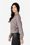 girl looking to her side wearing a light grey long sleeves sweater with black leggings