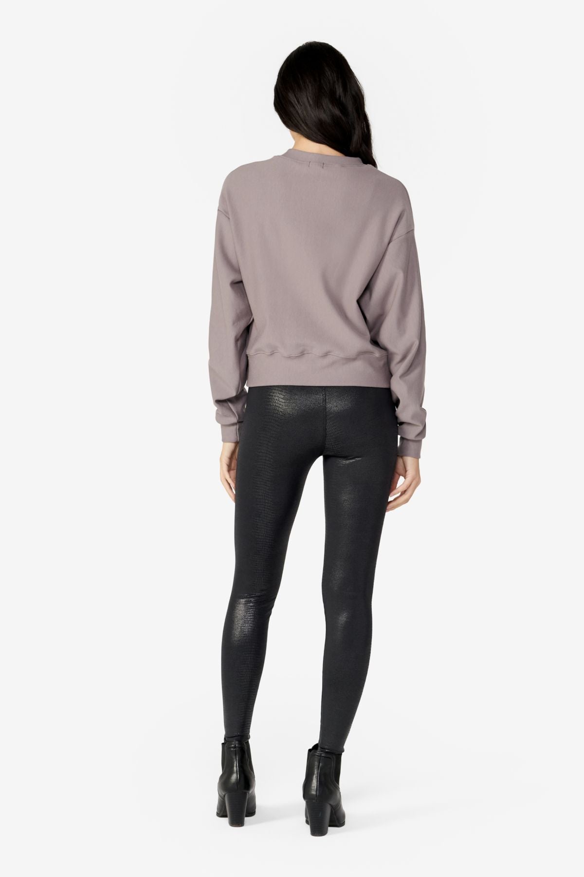 girl back side wearing a light grey long sleeves sweater with black leggings