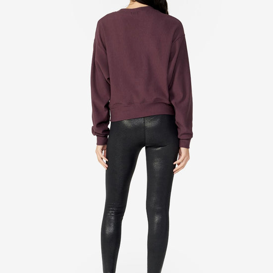 girl back side wearing a dark brown long sleeves sweater with black leggings and black boots
