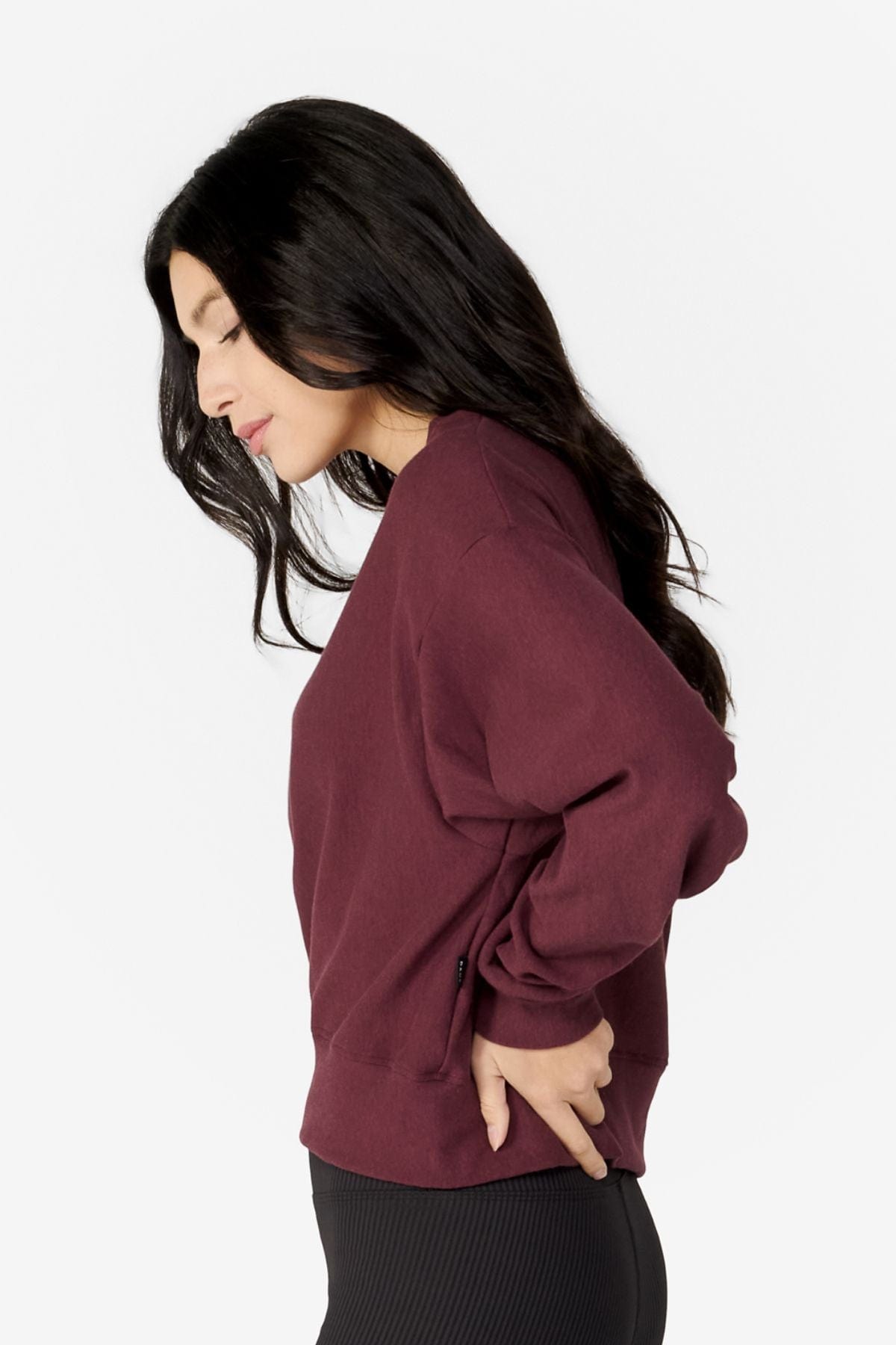 girl on her side wearing a dark red long sleeves sweater